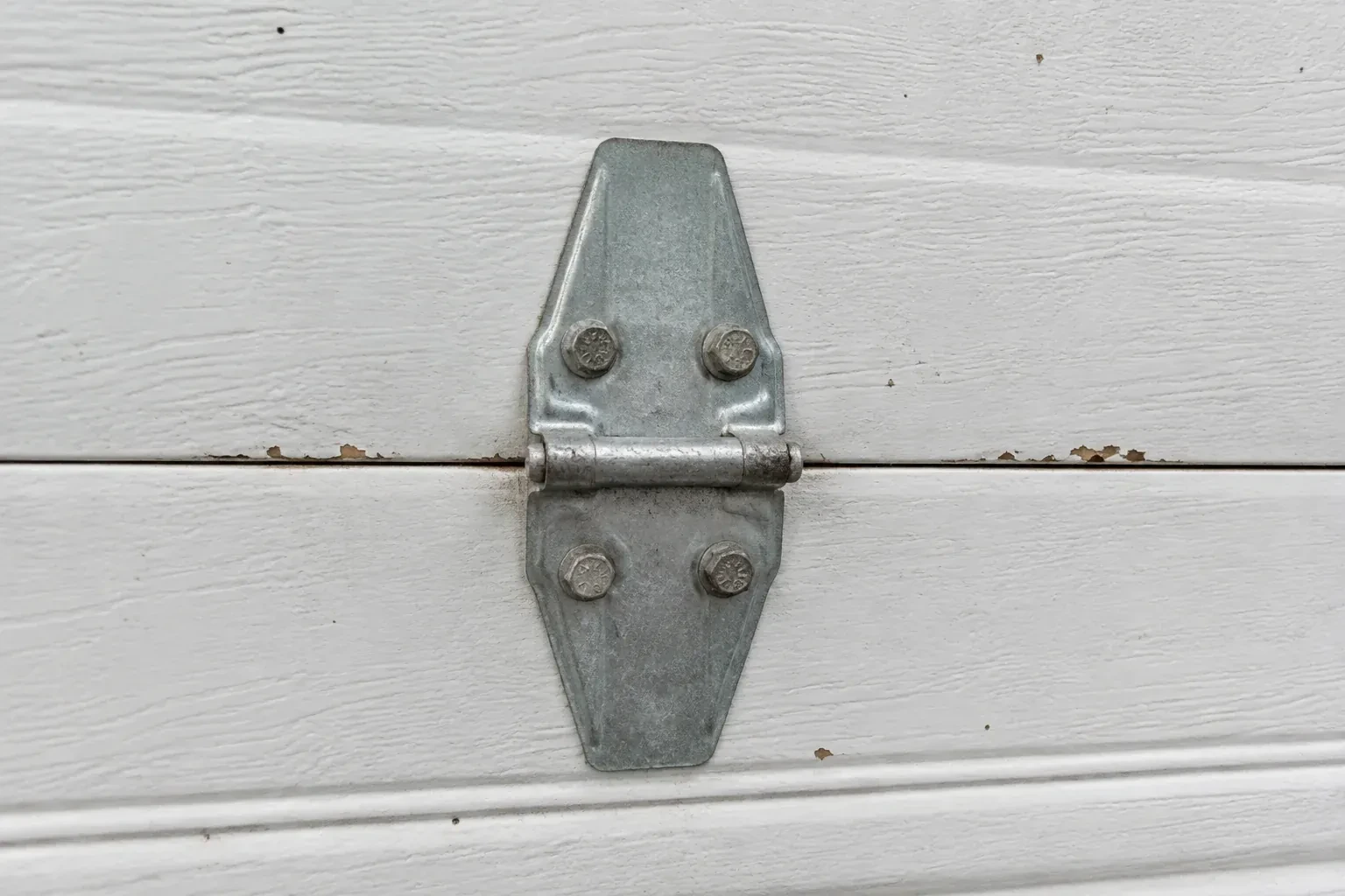 Metal center hinge across a seam in a white sectional garage door. — Garage Door Hinge Replacement, Oshawa